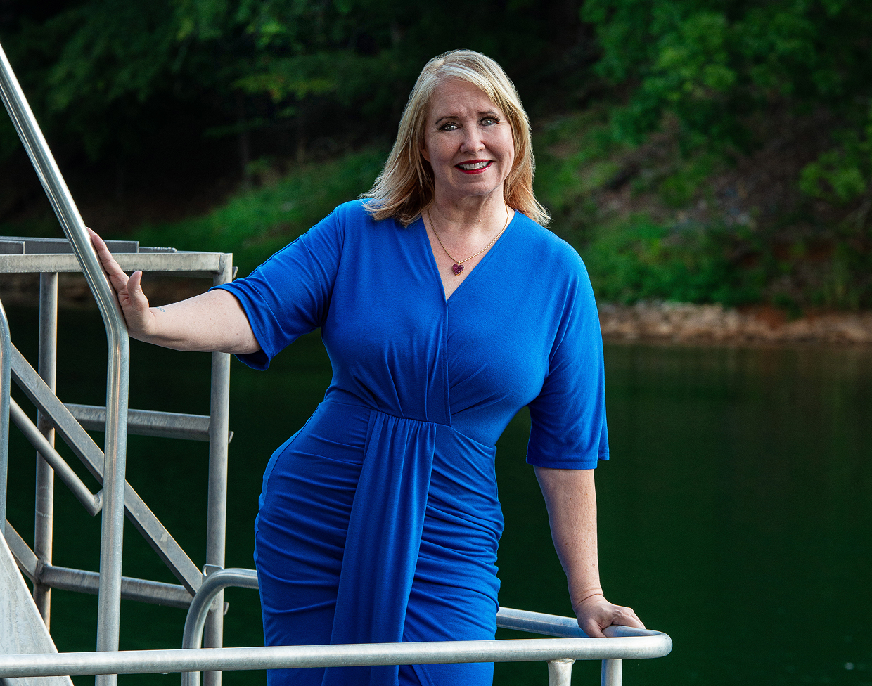 Woman in blue dress by a lake.