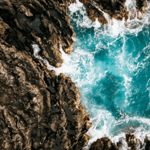 Rocky coastline with crashing turquoise waves.