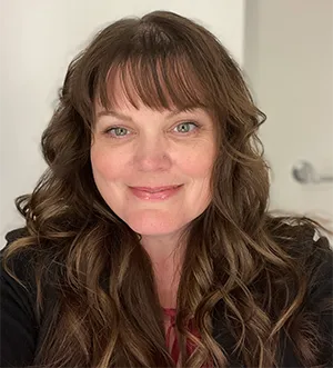Smiling woman with long brown hair indoors.